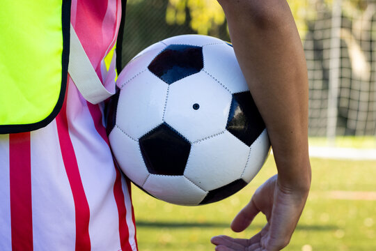 Holding soccer ball, person standing on field wearing sports jersey