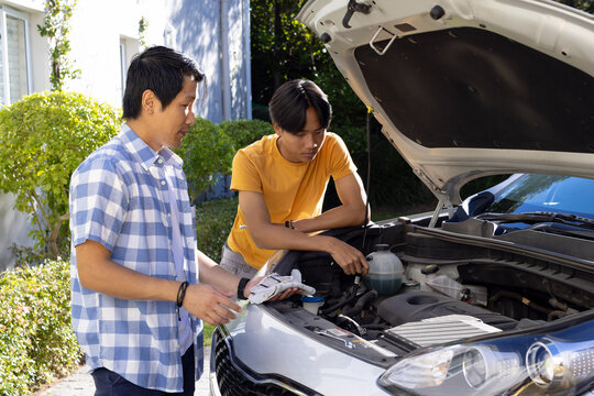 Checking car engine, father and son performing maintenance together outdoors