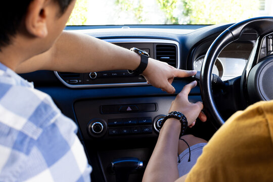 Pointing at car dashboard, asian man teaching another asian man driving skills