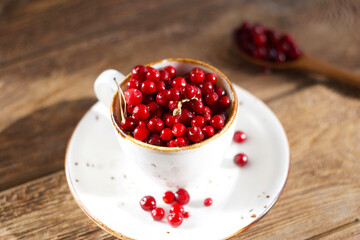 Lingonberries in a white mug on a wooden table