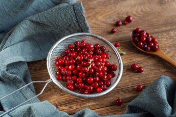 Lingonberries in a sieve lie on a wooden table