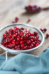 Lingonberries in a sieve lie on a wooden table