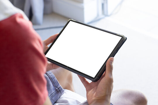 Holding tablet with blank screen, person sitting and browsing content, copy space