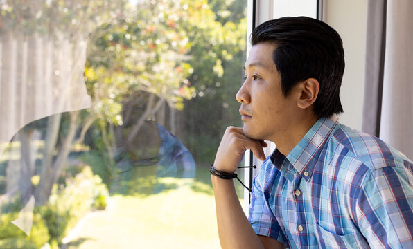 Contemplating outdoors, asian man in plaid shirt looking out window, copy space