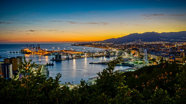 Panoramic view of Malaga city at sunset with the port in the foreground and the mountains in the background