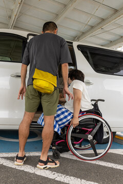 日本人の車椅子に乗った女性を男性が車に乗ろうとしている