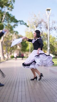 pareja de huasos bailando cueca chilena en la plaza de la ciudad