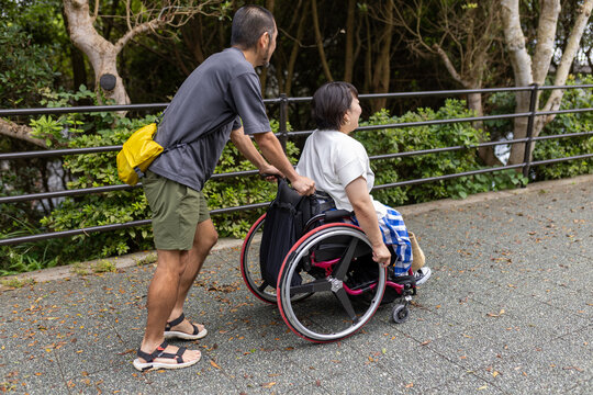 日本人の車椅子に乗った女性を男性が押して散歩を楽しんでいる