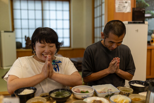 日本人の車椅子に乗った女性と男性のカップルが食事の前に手を合わせている