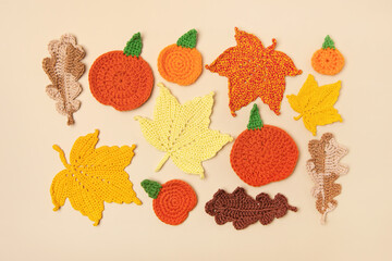 Autumn frame made of knitted toys in the shape of oak and maple leaves, orange pumpkins on beige background. Concept of autumn, Thanksgiving, Halloween
