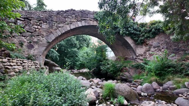 Paneo de c&aacute;mara en un paisaje panor&aacute;mico de campo en la orilla de un rio con un puente de piedra medieval