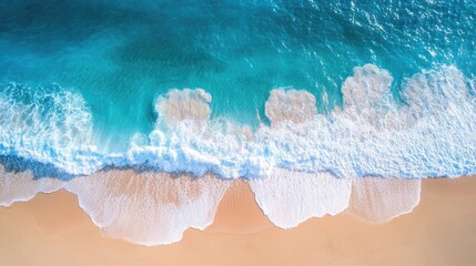Obraz premium Drone view of a bright blue sea with waves splashing and a golden sandy beach stretching out under the sun