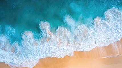 Drone view of a bright blue sea with waves splashing and a golden sandy beach stretching out under the sun