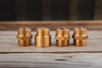 Brass plumbing fittings lying on a rustic wooden table on a sunny day (selective focus)