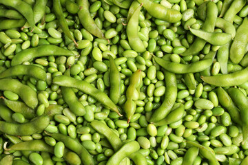 Fresh edamame beans and pods as background, top view