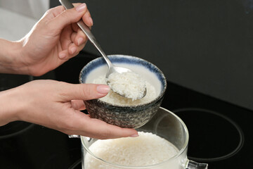 Woman taking boiled rice from pot into bowl, closeup