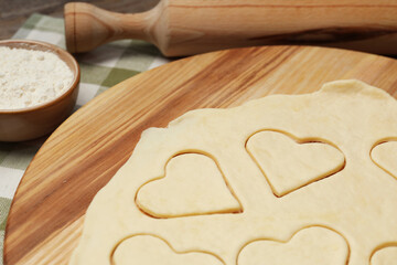 Raw dough and rolling pin on table, closeup