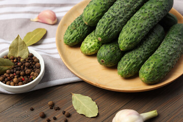 Fresh green cucumbers and spices on wooden table