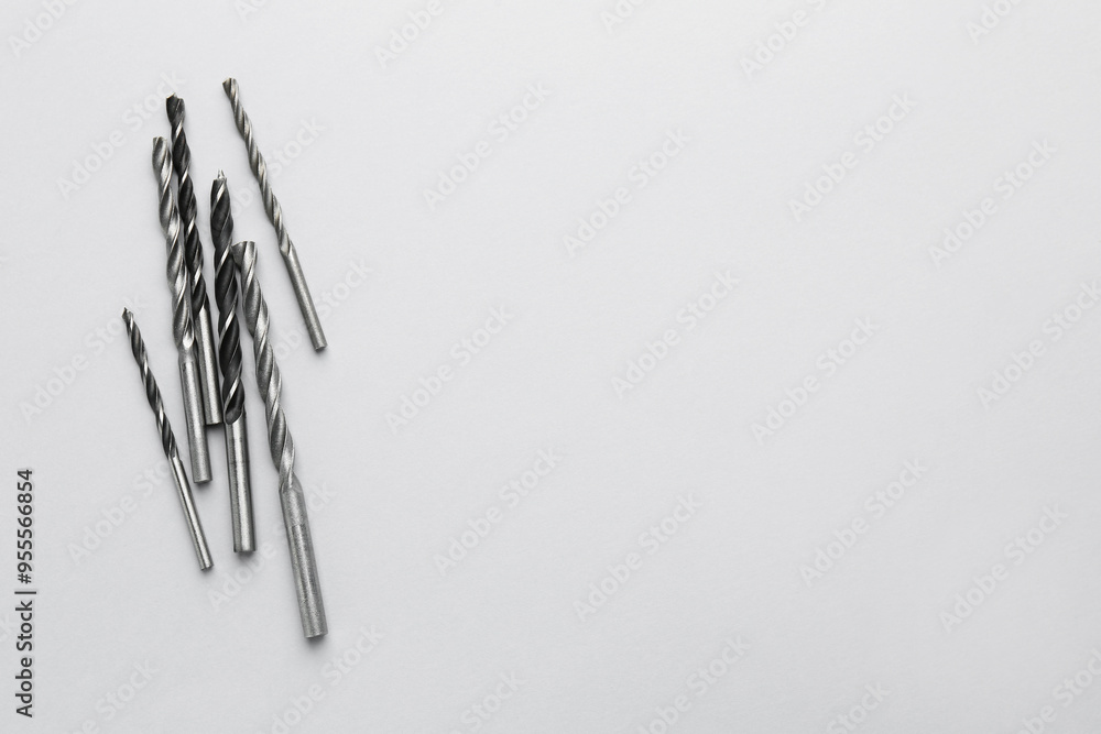 Wall mural Many different drill bits on light grey background, top view. Space for text