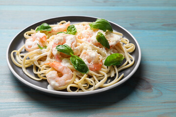 Tasty pasta with shrimps on light blue wooden table, closeup