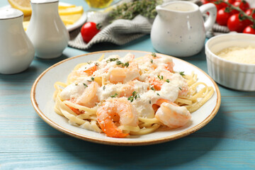 Tasty pasta with shrimps, creamy sauce and cheese on light blue wooden table, closeup