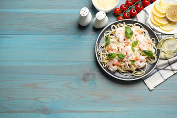 Tasty pasta with shrimps served on light blue wooden table, flat lay. Space for text