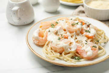 Tasty pasta with shrimps, creamy sauce and cheese on white marble table, closeup