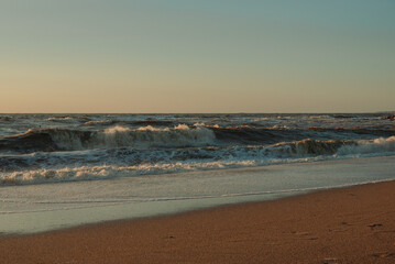 Sunset at sea during a storm. Coast with waves in sea on sunset. Waves in sea during storm and wind. Wave from the sea goes on land to the beach. Splashing Waves, Seaside.