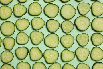 Slices of fresh cucumbers on turquoise background, flat lay