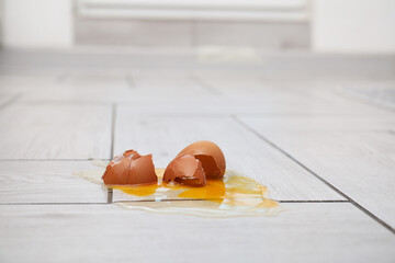 Raw broken egg on light wooden floor
