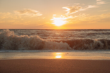 Obraz premium Sunset at sea during a storm. Coast with waves in sea on sunset. Waves in sea during storm and wind. Wave from the sea goes on land to the beach. Splashing Waves, Seaside.