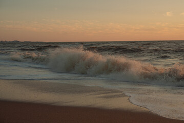 Sunset at sea during a storm. Coast with waves in sea on sunset. Waves in sea during storm and wind. Wave from the sea goes on land to the beach. Splashing Waves, Seaside.