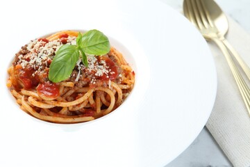 Delicious pasta bolognese with basil on table, closeup