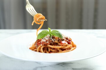 Eating delicious pasta bolognese at white marble table, closeup