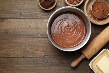 Chocolate dough in bowl and ingredients on wooden table, flat lay. Space for text