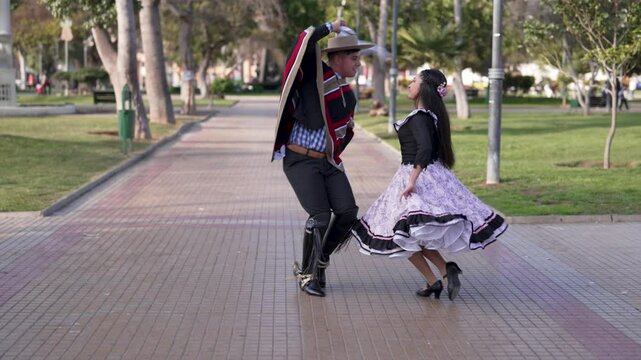 pareja de huasos bailando cueca chilena en la plaza de la ciudad