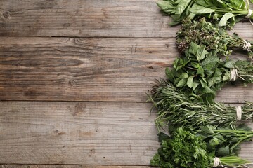 Bunches of different aromatic herbs on wooden table, flat lay. Space for text