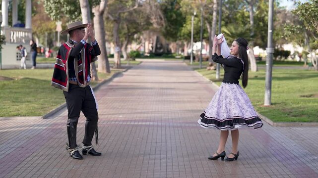 pareja de huasos bailando cueca chilena en la plaza de la ciudad