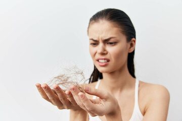 Hair loss concern, woman with thin hair, frustration expression, holding strands of hair in hand...