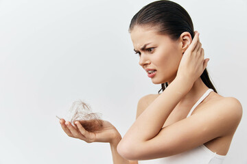 Hair loss struggle, woman with detached hair in hand, exhibiting concern and frustration, neutral...