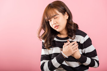 Fototapeta premium Young woman pressing on chest pain isolated on pink background, painful expression heartache, female having heart attack heart disease, Painful cramps