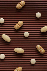Several yellow tablets and pills are randomly distributed across on brown textured background