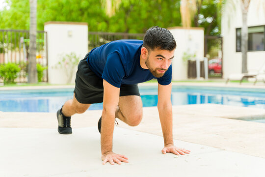 Young man doing mountain climber exercise poolside during a backyard workout session - Powered by Adobe