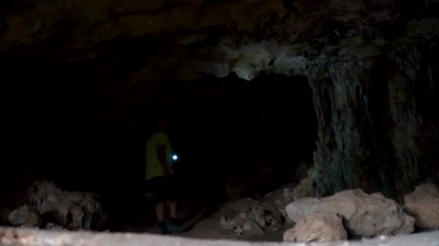 One man exploring a cave with a torch, real time