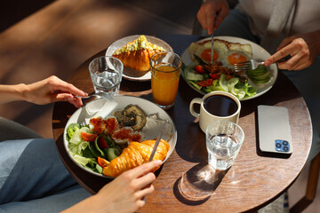 Couple having tasty breakfast at wooden table in cafe, closeup