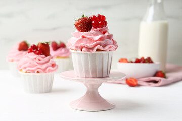 Tasty cupcakes with strawberries and red currants on white table