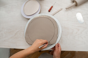 Using a sharp pottery carving knife to cut out a perfect round shape from clay. Ceramics class....