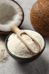 Coconut flour in bowl, scoop and fresh fruits on light grey table, closeup