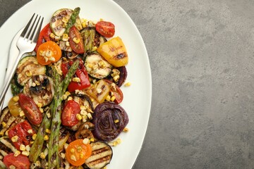 Delicious salad with grilled vegetables served on gray textured table, top view. Space for text