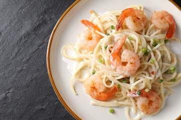 Delicious pasta with shrimps and green onion on black table, top view